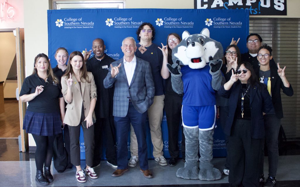 A group of people, including a mascot, pose together in front of a College of Southern Nevada backdrop.
